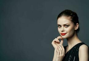 Charming lady in a black dress gestures with her hands on a gray background Copy Space photo