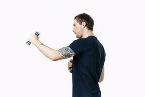 athlete in a black t-shirt are engaged in fitness on a white background indoors and dumbbells in hand photo