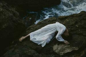 sensual woman in a white dress lying on a stone in a white dress Summer vacation concept photo