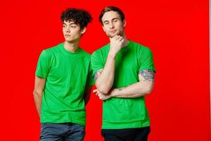 Two cheerful friends in green t-shirts are standing next to each other emotions isolated background photo