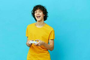 curly guy yellow T-shirt with joystick video games blue background photo