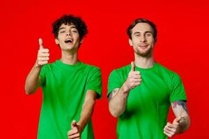 dos alegre amigos desde verde camisetas gesticular con manos emociones foto