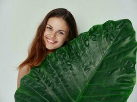 happy woman with green leaf on light background clean skin cosmetology model photo