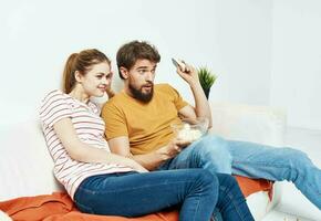 Fun man and energetic woman watching TV on the couch popcorn in a plate family communication photo