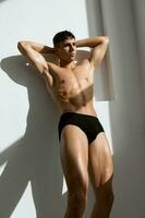 man in dark shorts with a pumped-up body on a light background no bottom photo