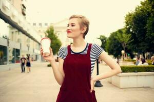 alegre mujer al aire libre caminando en vaso con Moda bebida foto