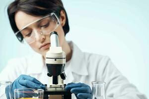 female laboratory assistant in a white coat with a microscope in the hands of a professional medicine technology photo