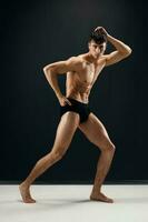 sporty man in black shorts posing on dark macho background photo