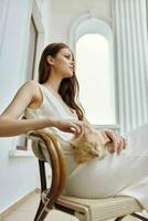 Woman in white dress stroking a cat sitting in a chair outdoors animals photo