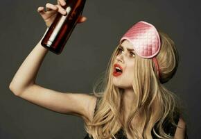 Woman with a bottle of beer and a pink sleep mask photo