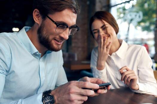 Cheerful man and woman are sitting in a cafe at the table working communication technology photo