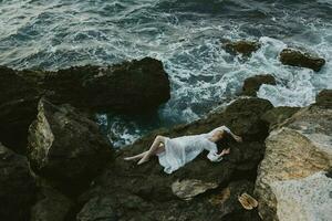 Beautiful bride Lies on his back on a stone cliff, cloudy weather view from above photo
