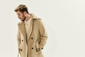 handsome man in beige coat hands in pocket side view cropped view studio photo