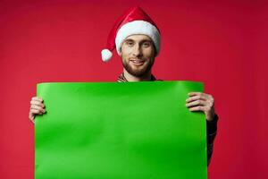 Cheerful man in a santa hat holding a banner holiday isolated background photo