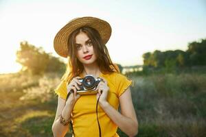 bonito mujer con cámara en naturaleza Fresco aire sombrero rojo labios pasatiempo foto