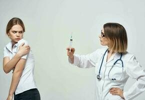 Frightened patient and nurse with a syringe in hand on a light background photo