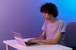 curly guy in front of laptop entertainment violet background photo