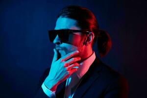 handsome man in a jacket posing self confidence sunglasses dark background photo