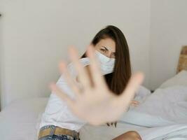 woman in medical mask in quarantine covered her face with palm aggression protest photo