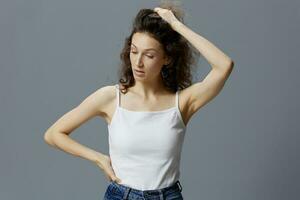 Irritated angry curly beautiful woman in basic white t-shirt trying to calm down holding her hair posing isolated on over gray blue background. People Lifestyle Emotions concept. Copy space photo