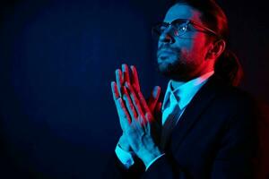 handsome man gestures with his hands with glasses dark background photo