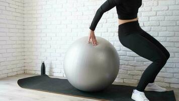 fitness, sport en een gezonde levensstijl. jonge vrouw die thuis traint met stabiliteitsbal of fitnessbal. thuistraining video