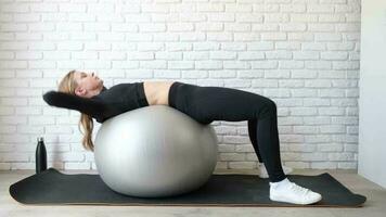 fitness, sport e stile di vita sano. giovane donna che lavora a casa con una palla di stabilità o una palla fitness. allenamento a casa video