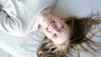 Top view of smiling young woman falling on comfortable bed in cozy bedroom and laughing, relaxation concept video