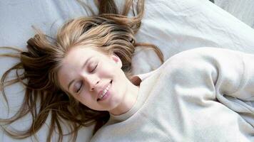 topo Visão do sorridente jovem mulher queda em confortável cama dentro acolhedor quarto e rindo, relaxamento conceito video