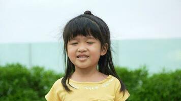 portrait marrant peu asiatique fille gros souriant enfant à la recherche à caméra et montrer du doigt sa joues, profiter enfance témoignage concept, positif enfant, 4k images, lent mouvement portrait video