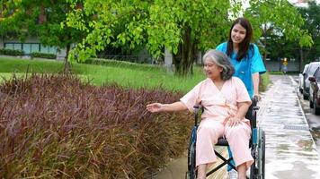 Aziatische zorgvuldige verzorger of verpleegster die voor de patiënt in een rolstoel zorgt. concept van gelukkig pensioen met zorg van een verzorger en spaar- en senior ziektekostenverzekering, een gelukkig gezin video