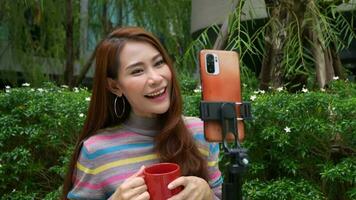 Beautiful Asian woman female blogger use smartphone for broadcasts live on social networks, speaks via video calling on a mobile phone, content creator, influencer and communication concept.