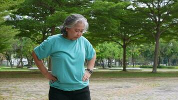 Aging mature woman do fitness outdoors in park at morning, fitness concept Taking care of the physical health of the elderly. Concept of health care of seniors, cardio workout in park at morning video