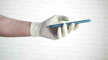 médico mão dentro látex luvas segurando inteligente telefone com esvaziar tela video