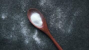 close up of pink rock salt and wooden spoon on black background video