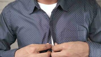 Man buttoning his shirt close up video