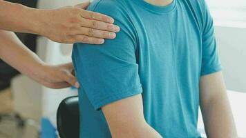 médico ou fisioterapeuta trabalhando examinando tratando ferido braço do atleta masculino paciente, alongamento e exercício, fazendo a reabilitação terapia dor dentro clínica. video