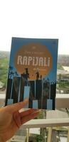 Bekasi, Indonesia in July 2022. A hand is holding a novel titled Rapijali First Edition with the subtitle Mencari by Dee Lestari photo