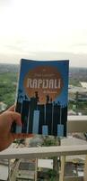 Bekasi, Indonesia in July 2022. A hand is holding a novel titled Rapijali First Edition with the subtitle Mencari by Dee Lestari photo