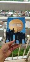 Bekasi, Indonesia in July 2022. A hand is holding a novel titled Rapijali First Edition with the subtitle Mencari by Dee Lestari photo