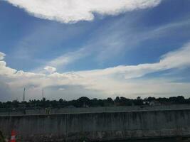 Blue sky surrounded by white clouds that were slightly grayish. photo