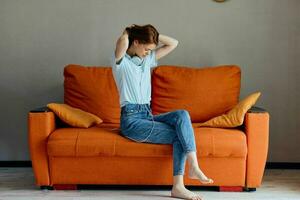 cheerful woman listening to music with headphones on the orange sofa Lifestyle photo