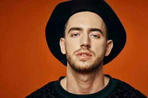 hermoso hombre en negro sombrero estudio posando naranja antecedentes foto