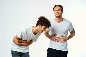 dos gracioso amigos en blanco camisetas riendo positivo emociones foto