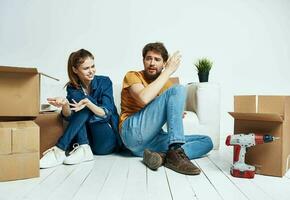 A man and a woman are sitting on the floor with open boxes and tools for repair photo