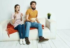 Men women with popcorn in a plate indoors on the sofa photo