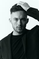 Modelling snapshots. Closeup portrait of self-confident attractive handsome muscular guy man in jacket looks at camera sitting on chair in white studio background. Black and White concept. Copy space photo