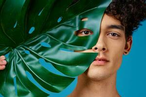 handsome man green leaf face closeup blue background photo