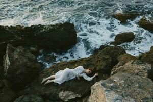 Beautiful bride lying on rocky coast with cracks on rocky surface vacation concept photo