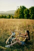 mujer sentado en campo con perro tejonero perro sonriente mientras gasto hora en naturaleza con amigo perro en otoño a puesta de sol mientras de viaje foto